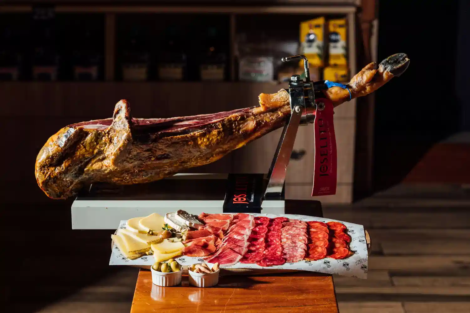 Jamón ibérico de bellota entier sur un support en bois dans une pièce à température ambiante, méthode de conservation traditionnelle.