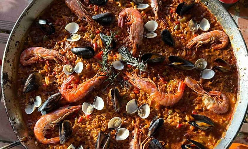 Cuisson en direct paella géante extérieur événement convives lumière chaude