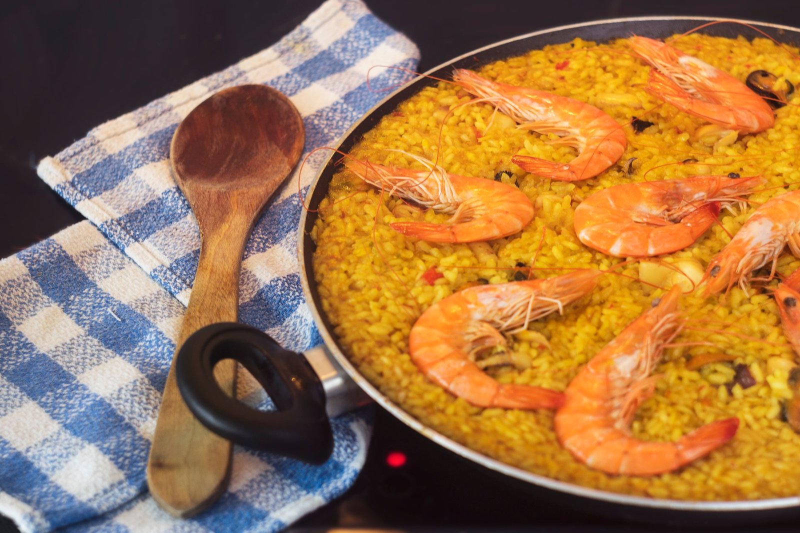 Plat de nouilles fines aux fruits de mer servi dans sa poêle avec quartiers de citron