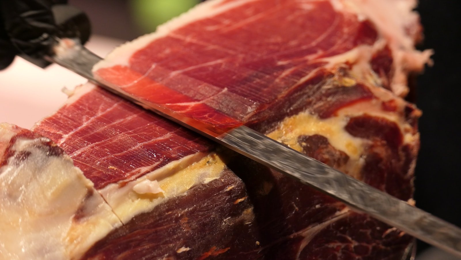 Tranches fines de jambon ibérique disposées sur planche en bois pour apéritif