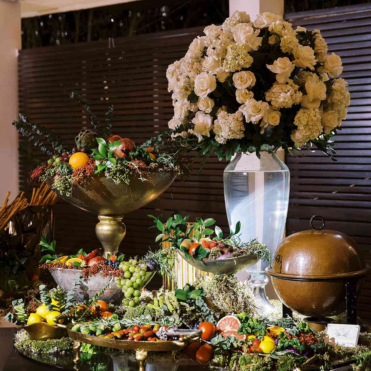 Estación de aperitivos en evento corporativo con múltiples alturas y luz ambiental