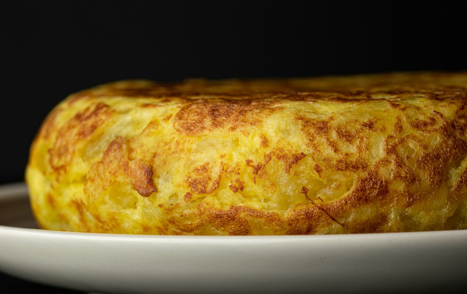 Part d'omelette espagnole coupée montrant un cœur crémeux et des rondelles de pomme de terre