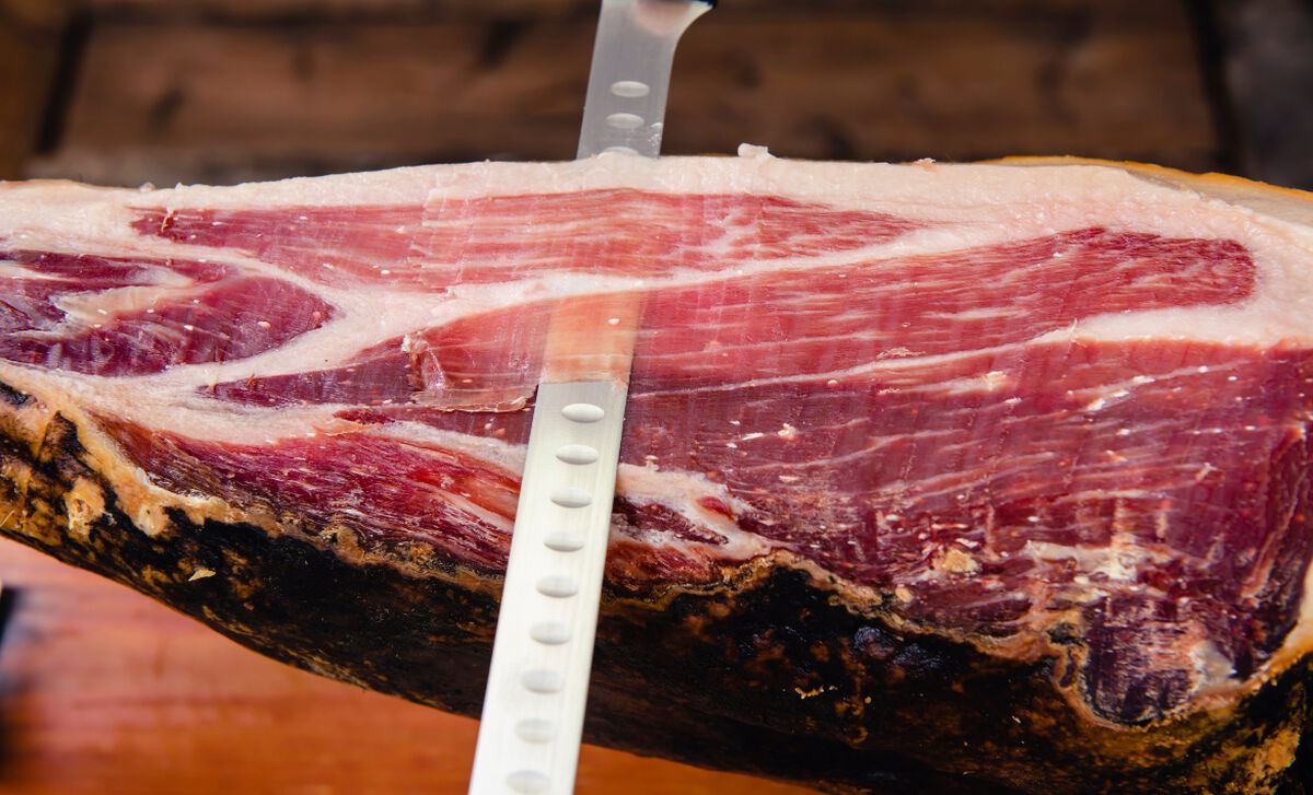 Tranches fines de charcuterie ibérique disposées en éventail sur planche en bois