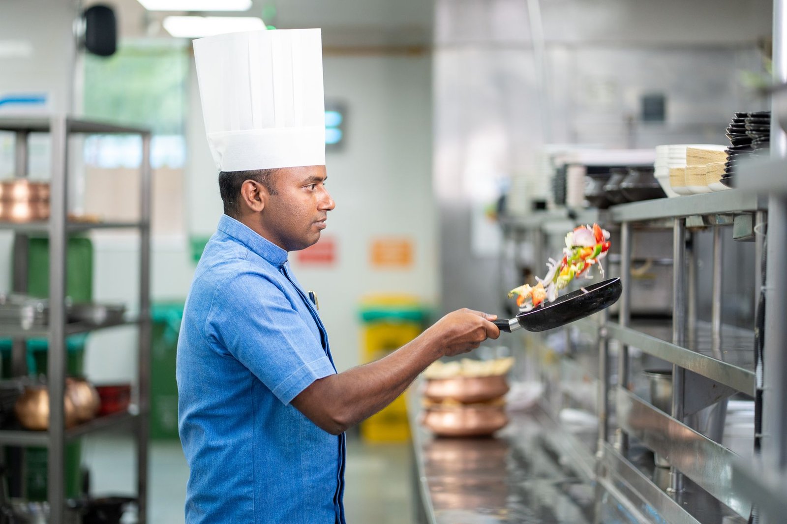 Cuisinier retournant une omelette épaisse à l'aide d'une assiette posée sur la poêle