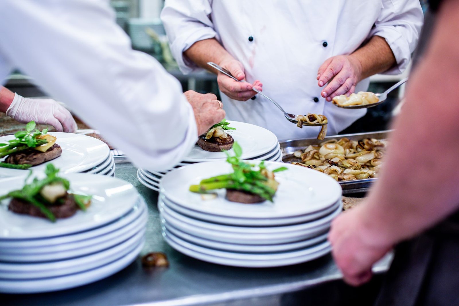Cuisiniers dressant des assiettes au passe pendant un service chronométré