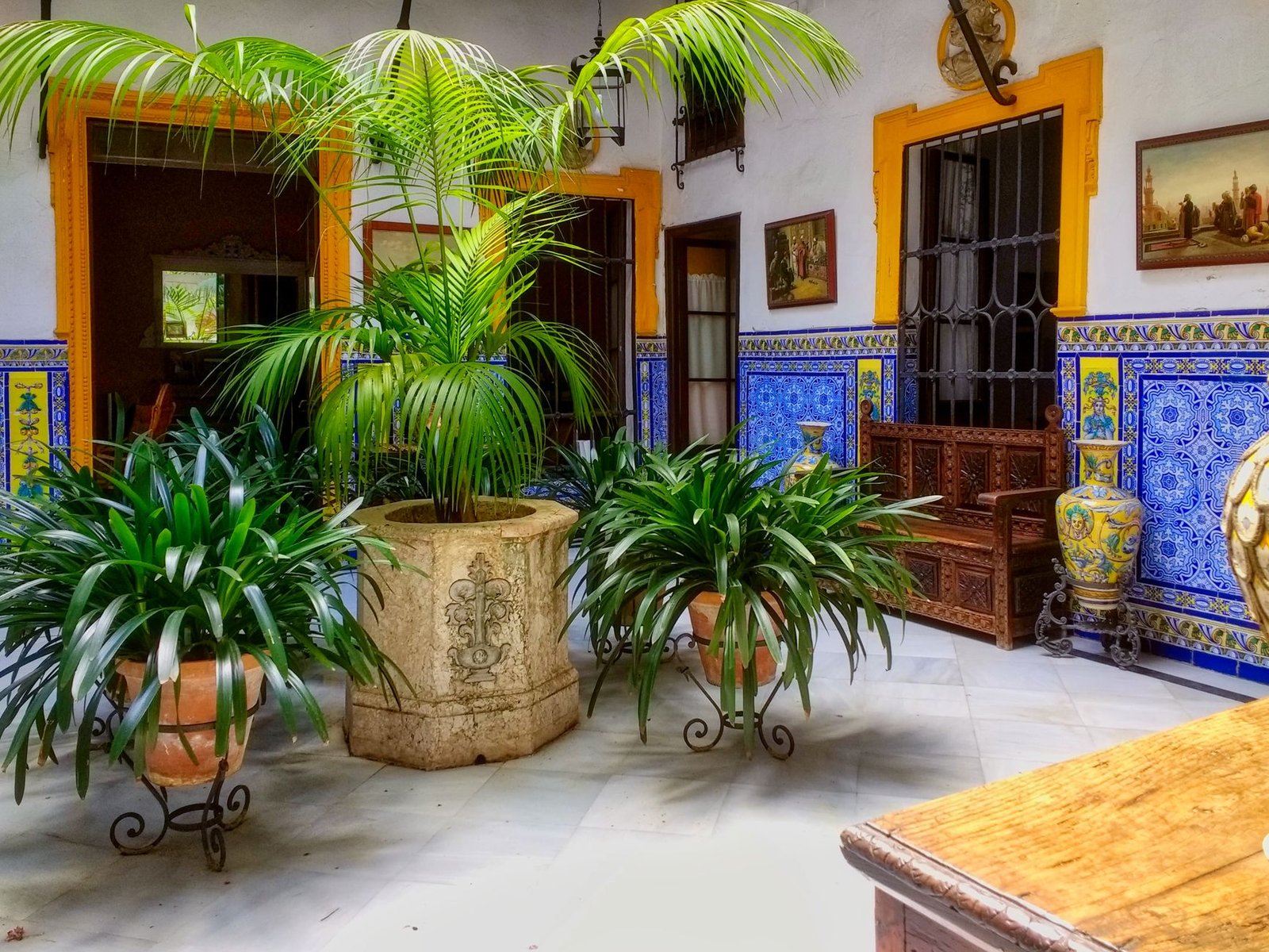 Patio andalou aux murs chaulés et azulejos bleus en lumière de fin de journée