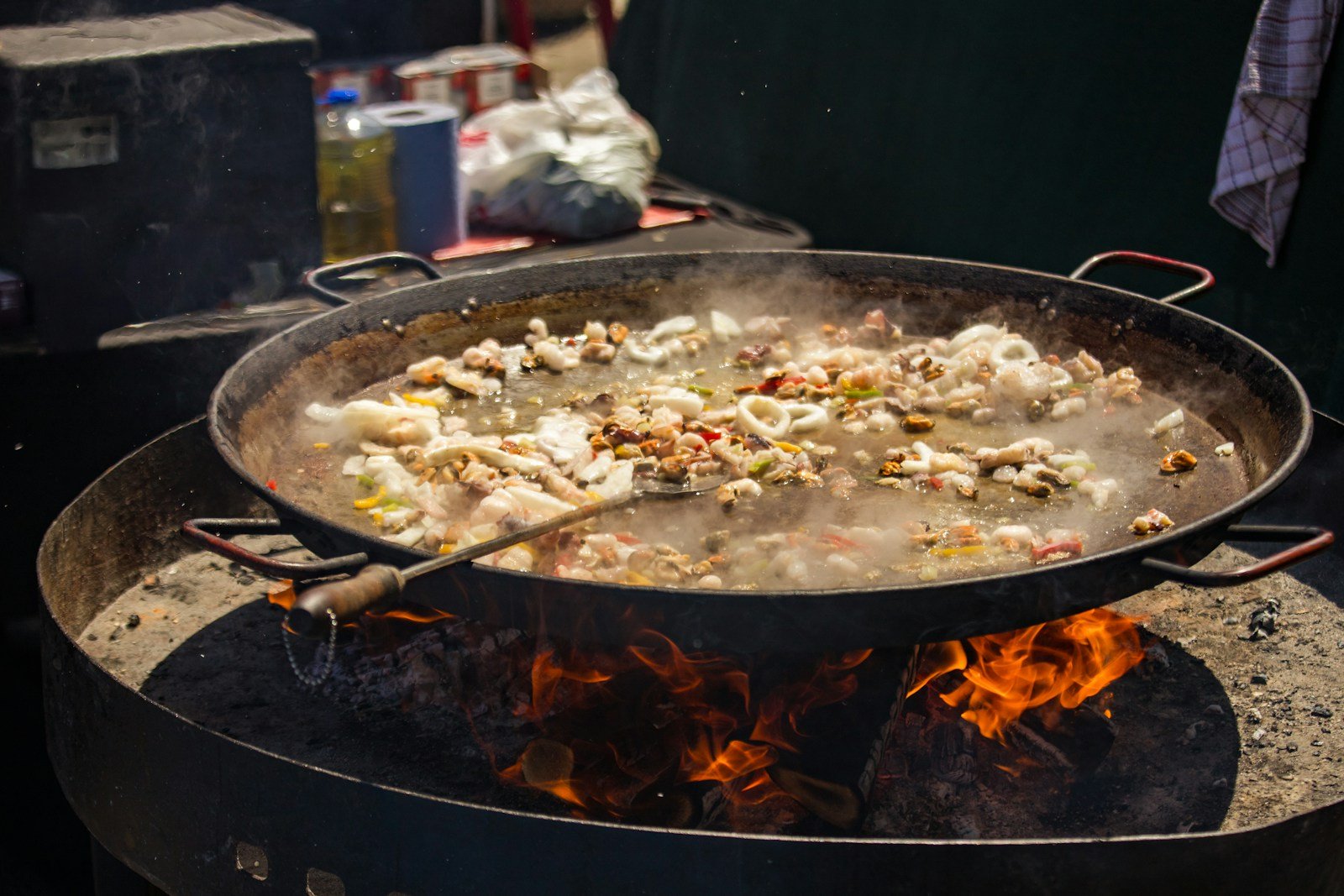Grande poêle en acier sur feu de bois avec riz étalé en couche fine